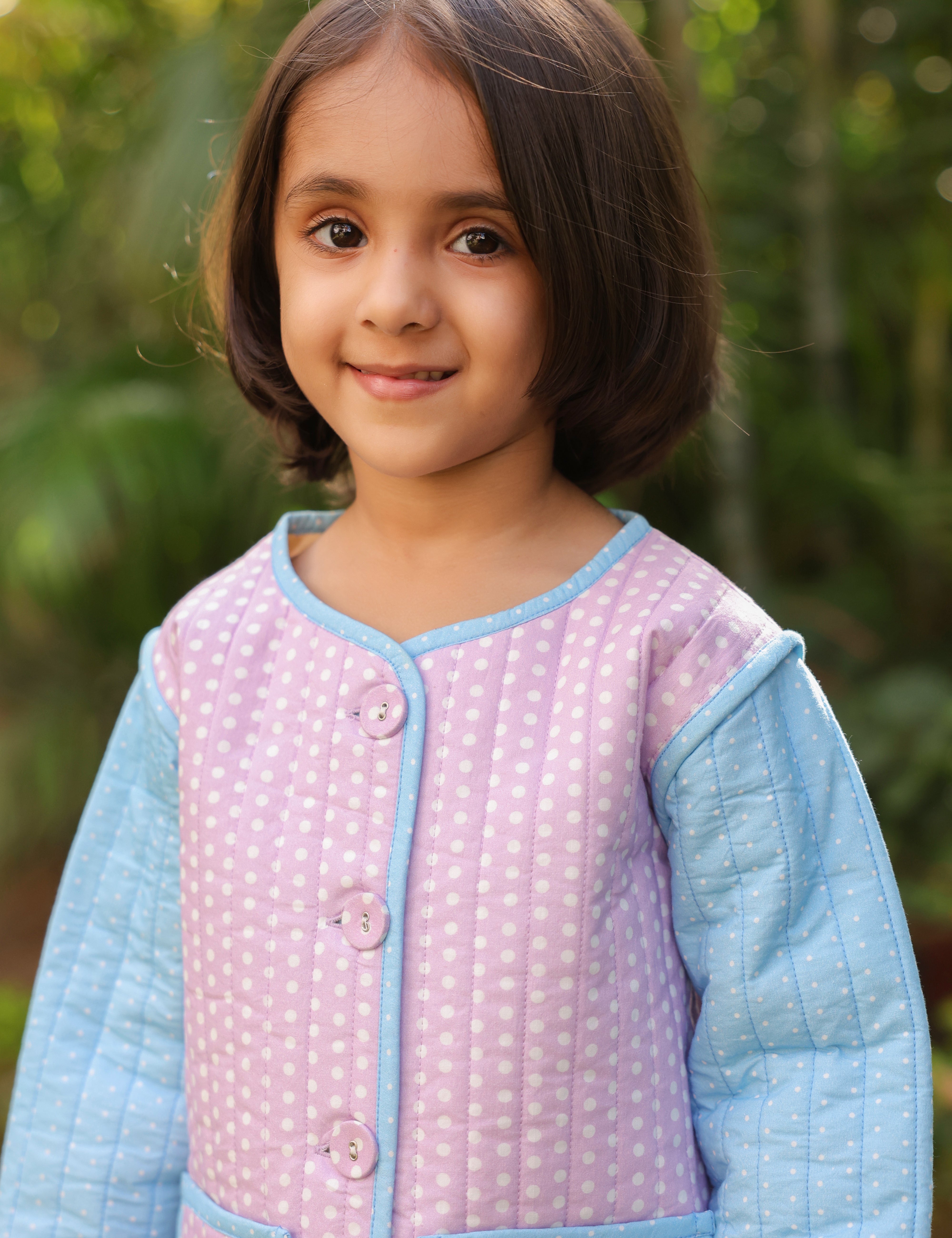 Girl wearing purple polka dot quilted cotton jacket with blue jeans